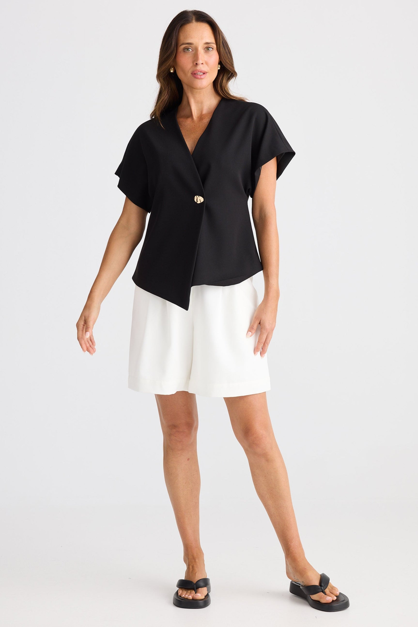 Woman wearing a black top and white shorts on a white background