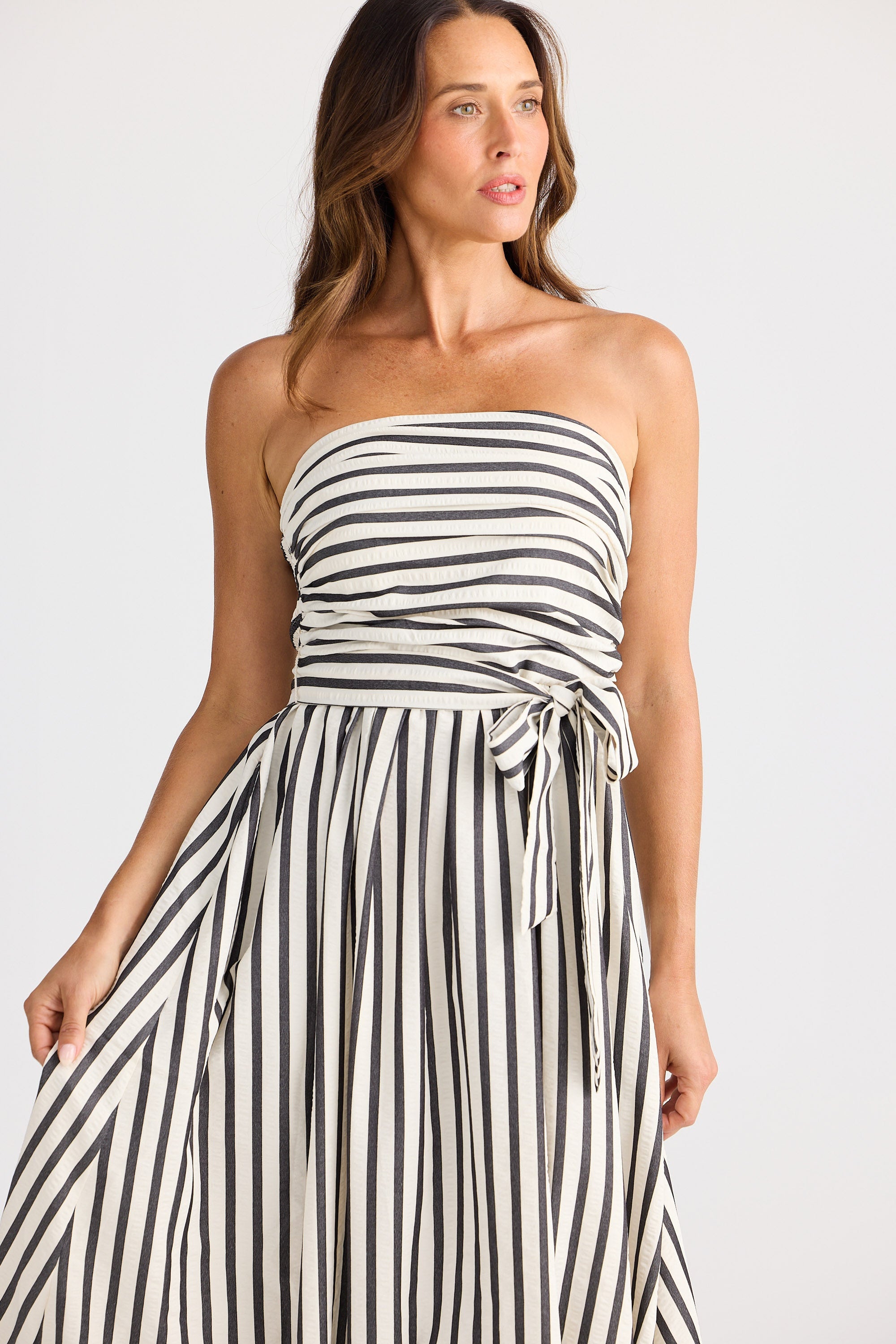 Woman wearing a black and white striped strapless dress on a white background