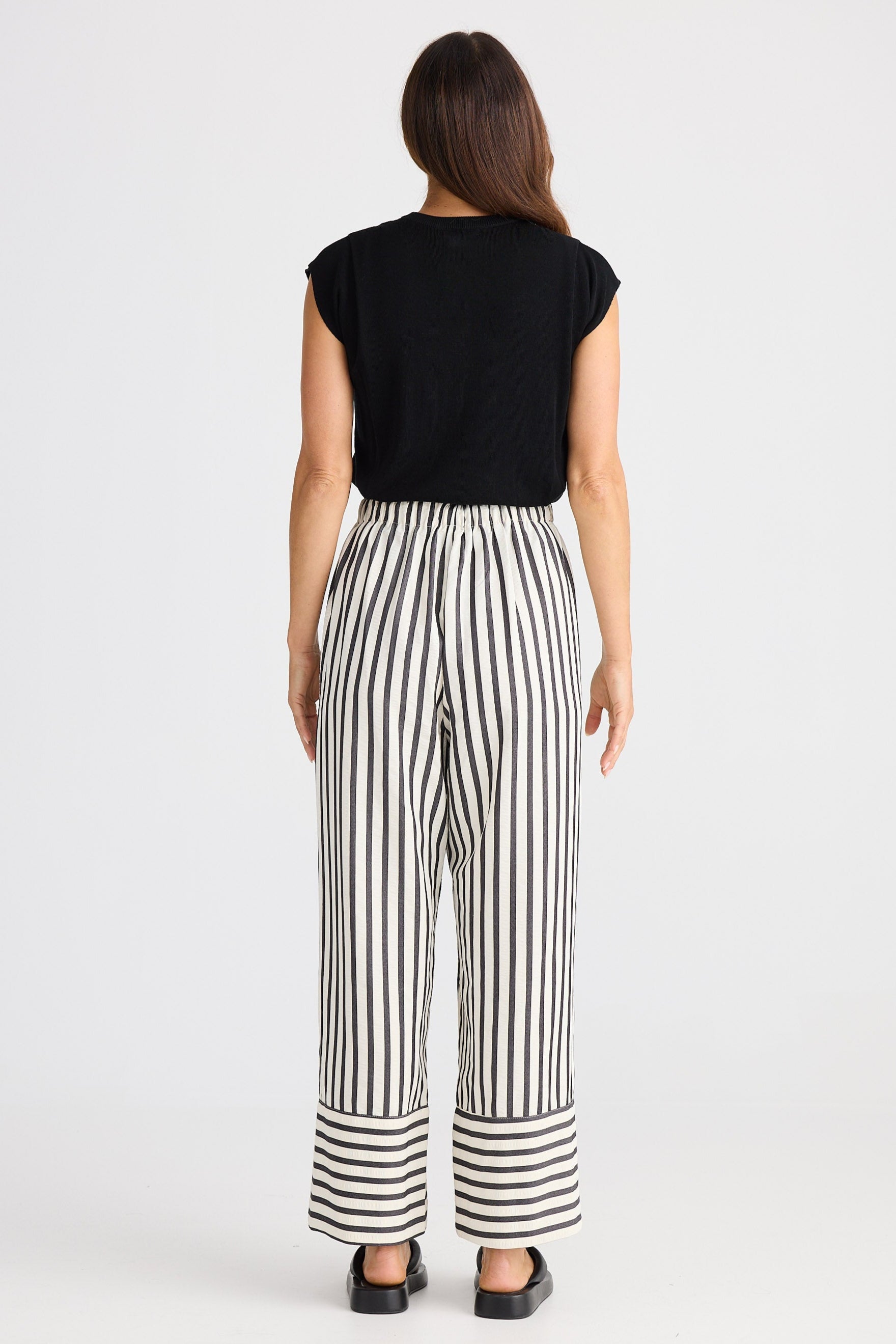 Woman wearing a black top and striped pants on a white background